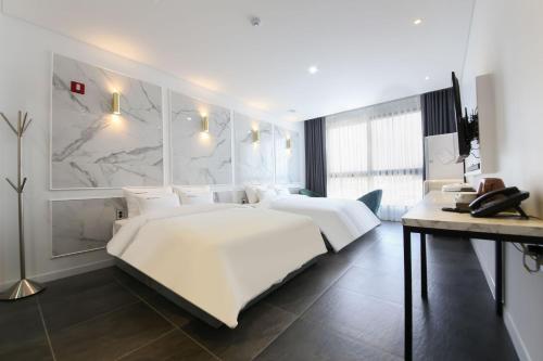 a bedroom with a large white bed and a desk at Hotel Raum Suncheon in Suncheon