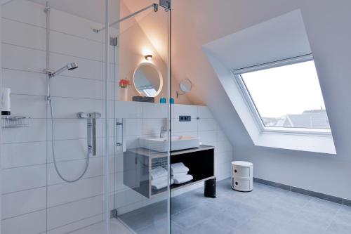 W łazience znajduje się szklana kabina prysznicowa i umywalka. w obiekcie Bett&Bude Boardinghouse w mieście Westerland