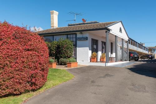 a building with a red bush in front of it at Blue Mountains Highway Motel in Katoomba