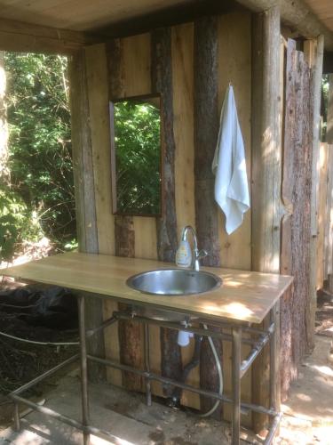 ein Bad mit einem Waschbecken und einem Spiegel in der Unterkunft Treehouse B&B in Rabjerg