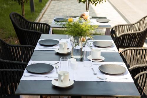 a table with black tables and chairs with plates and glasses at Hotel Florian&Godler in Karlovac