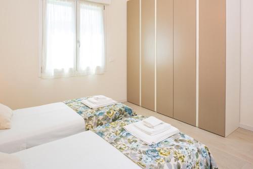 a white bedroom with two beds and a closet at Bivio Family House By Case al Lago in Peschiera del Garda