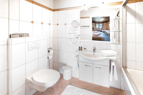 a white bathroom with a toilet and a sink at Hotel Seewinkel in Fuschl am See