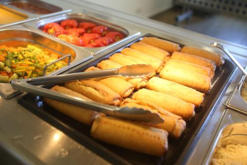 a tray of hot dogs with tongs and other foods at Jugendherberge Westerland in Westerland (Sylt)