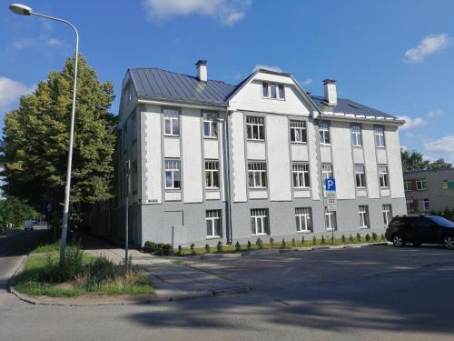 a large white building with a car parked in front of it at S7 Apartment in Rīga