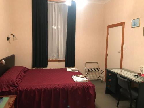 a bedroom with a bed and a desk and a window at Feilding Hotel in Feilding