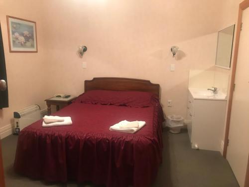ein Schlafzimmer mit einem roten Bett mit zwei Handtüchern darauf in der Unterkunft Feilding Hotel in Feilding