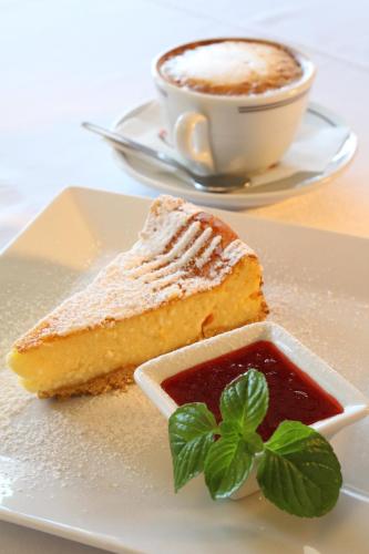 a plate with a piece of cake and a cup of coffee at Tó Wellness Hotel in Bánk