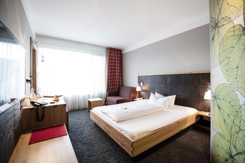 ein Hotelzimmer mit einem Bett und einem Stuhl in der Unterkunft Hotel Linde in Günzburg