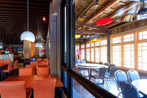 a dining room with tables and chairs and windows at 埔里夏都華蔓山林日式會館 Puli Huaman Villa in Puli
