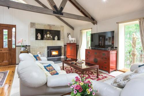 a living room with white furniture and a fireplace at The Stone on the Hill - 3 bedroom house in Kallista