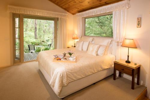 Un dormitorio con una cama grande y una ventana en Myers Creek Cascades Luxury Cottages, en Healesville