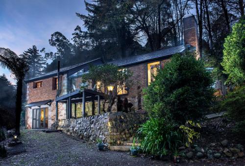 a brick house with windows and a stone wall at The Stone on the Hill - 3 bedroom house in Kallista