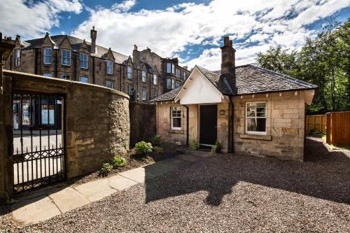an old stone house with a gate and a building at Trinity Lodge - Home with Private Garden and Parking in Edinburgh