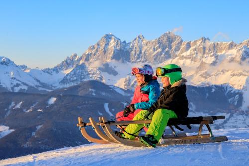 two people sitting on a sled on a snow covered mountain at Appartement Panorama in Gröbming