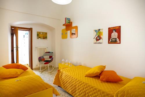 two beds in a bedroom with yellow sheets at Il Segnalibro B&B in Alberobello