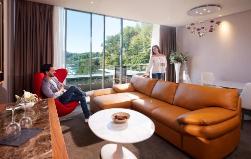 two people sitting in a living room with a couch at Atlantida Boutique Hotel in Rogaška Slatina