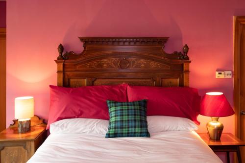 a bedroom with a bed with a red wall at Powdermills B & B in Inveraray