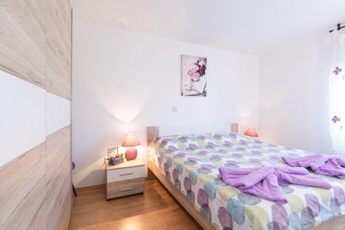 a bedroom with a bed with purple blankets on it at Apartment Adrijana in Vrbnik