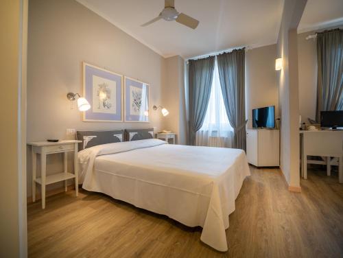 una camera da letto con un letto bianco e una televisione di Hotel Bel Soggiorno a San Gimignano