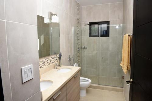 Un baño con dos lavabos, un inodoro y una ducha. en Casa Boroda, en La Garita