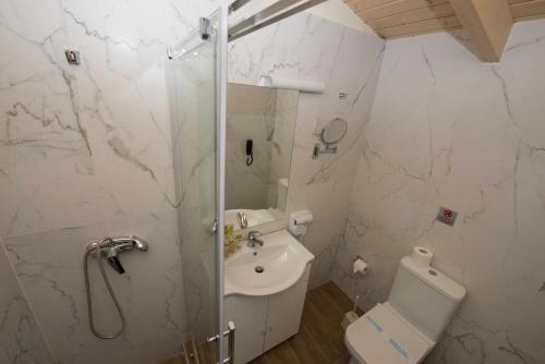 a bathroom with a shower and a toilet and a sink at Amour Holiday Resort in Sidari