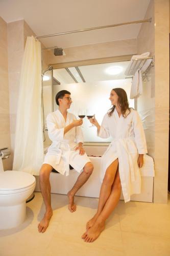 een man en een vrouw zitten op een badkuip in een badkamer bij Westlake Hotel & Resort Vinh Phuc in Yen