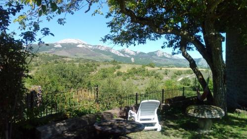 a white chair sitting under a tree with mountains in the background at Kukuma Etxea Habitaciones con derecho a cocina in Galarreta