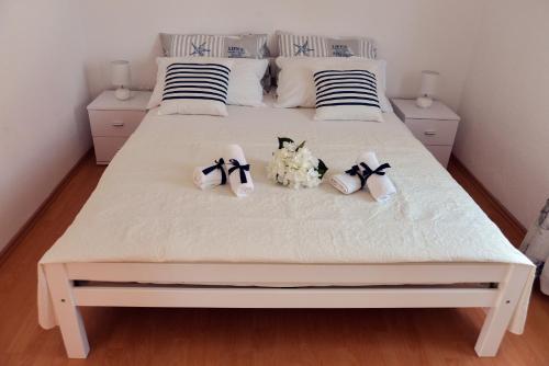 a white bed with shoes and flowers on it at City roof top Apartment Cambi in Kaštela