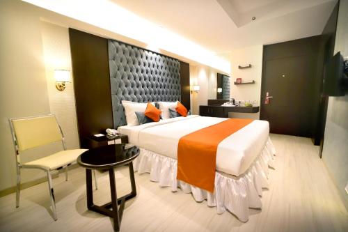 ein Hotelzimmer mit einem großen Bett und einem Stuhl in der Unterkunft Southern Plaza in Kalkutta