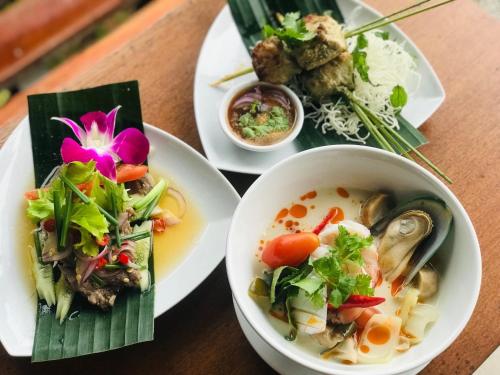 a table with plates of food and a bowl of soup at Koh Yao Yai Hillside Resort in Ko Yao Yai