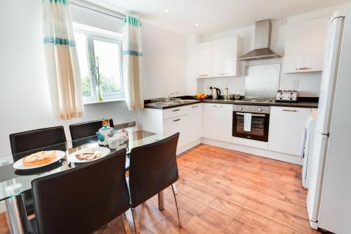 a kitchen with white cabinets and a table and chairs at Meridian Apartment Suites in Southend-on-Sea