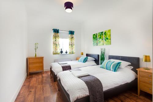 3 posti letto in una camera con pareti bianche e pavimenti in legno di Meridian Apartment Suites a Southend-on-Sea