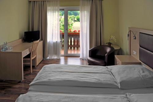 a bedroom with a bed and a desk and a chair at Hotel Tannenhof in Steinen