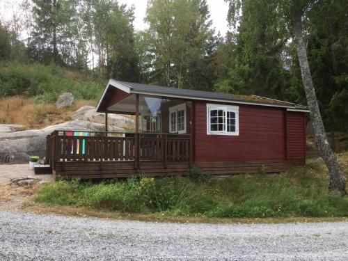 een kleine rode hut met een veranda bij Stuga utanför Fjällbacka in Fjällbacka