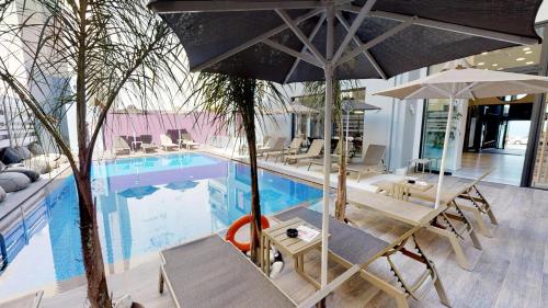 a swimming pool with chairs and umbrellas next to at Medusa Apartments in Rethymno Town