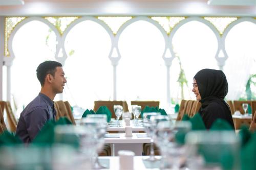 a man and woman sitting at a table in a restaurant at Alfahad Hotel in Hat Yai