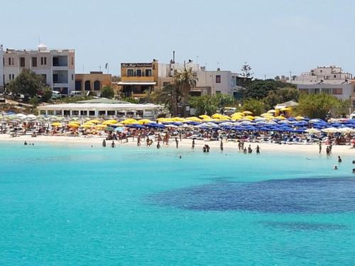 a group of people on a beach with umbrellas at Stella Marina in Lampedusa