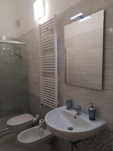 a bathroom with a sink and a toilet and a mirror at Casa Midori in Lecce