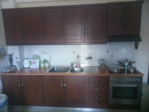 a kitchen with wooden cabinets and a sink at New Apartment Tsouris ~Makrys Gialos~ in Makry Gialos