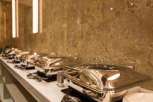 a row of stainless steel sinks in a bathroom at Hotel Wego in Mumbai