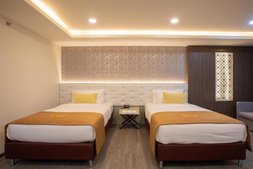 a hotel room with two beds and a couch at Alfahad Hotel in Hat Yai