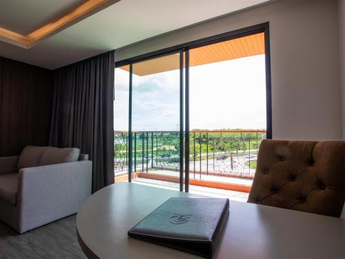 a room with a table and a chair and a large window at Alfahad Hotel in Hat Yai