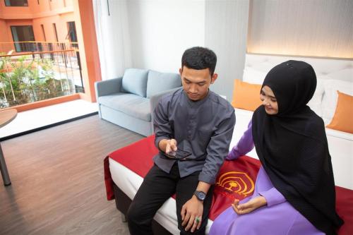 a man and a woman sitting on a bed at Alfahad Hotel in Hat Yai