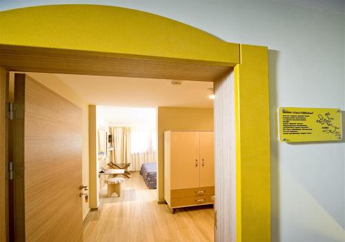 a room with a yellow wall and a hallway at Ion Slow City Adult 12 in Siğacık