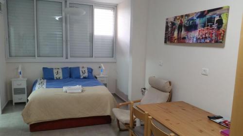 Schlafzimmer mit einem Bett, einem Schreibtisch und einem Tisch in der Unterkunft Herzliya Center Apartments in Herzlia