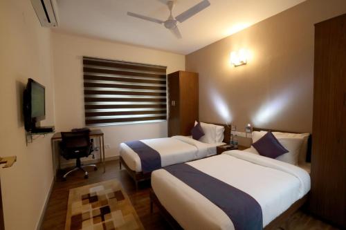 a hotel room with two beds and a television at Crest Executive Suites, Whitefield in Bengaluru