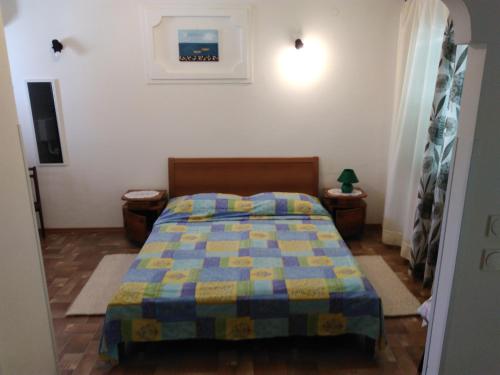 een slaapkamer met een bed met een blauwe en gele quilt bij Ina in Funtana