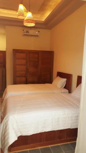 a bedroom with a large white bed with a wooden headboard at Pink Tulip Hoi An in Hoi An