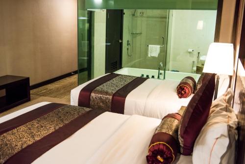 two beds in a hotel room with a bath tub at Royale Signature Hotel in Alor Setar